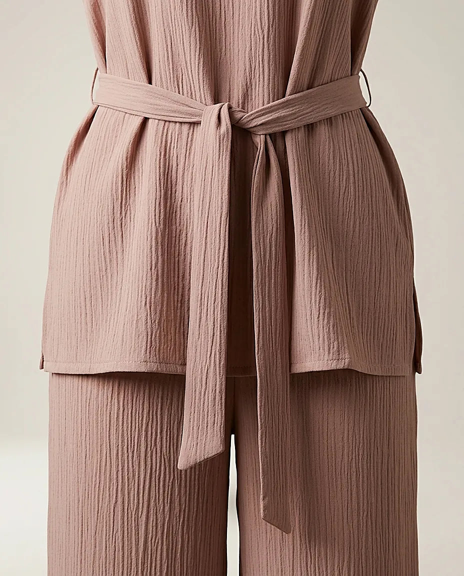 Compleu de damă elegant-casual din două piese, culoare bej-maroniu, cu bluză lejeră, mâneci scurte și pantaloni largi, cordon în talie și textură creponată