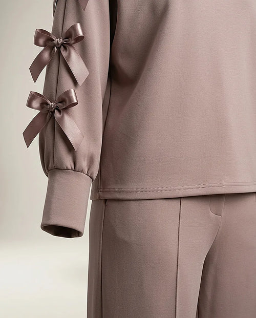 Compleu de damă elegant-casual din două piese, culoare taupe rozaliu, cu bluză cu mâneci decupate și fundițe satinate și pantaloni palazzo