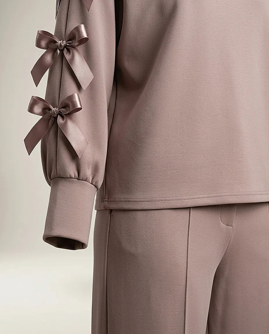 Compleu de damă elegant-casual din două piese, culoare taupe rozaliu, cu bluză cu mâneci decupate și fundițe satinate și pantaloni palazzo