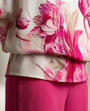 Compleu elegant de damă din două piese, cu bluză albă vaporoasă cu imprimeu floral roz și pantaloni evazați fucsia