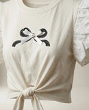 Tricou alb de damă cu mâneci scurte cu volane, imprimeu fundă și nod decorativ în față