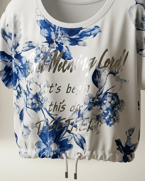 Tricou de damă alb cu imprimeu floral albastru și text argintiu metalizat, mânecă scurtă cu șnur în talie, stil casual