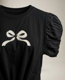 Tricou negru de damă cu mâneci scurte bufante, imprimeu fundă și nod decorativ în talie, stil casual-elegant